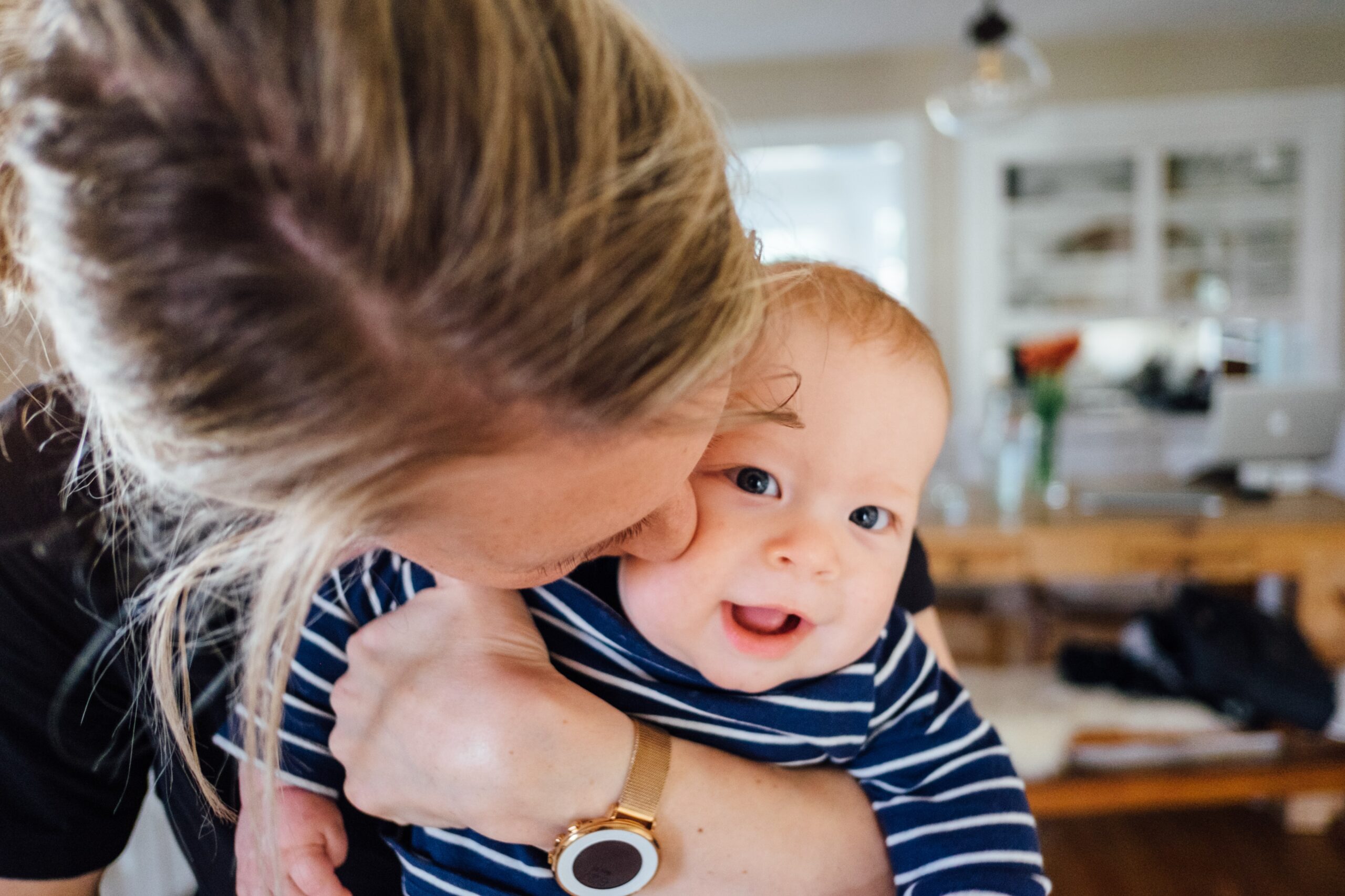 Young mother kissing the cheek of a happy baby